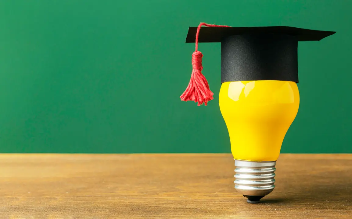 A light bulb with a graduation hat, demonstrating the blog Maynooth University Scholarship.