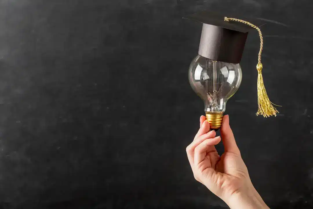 Person holding light bulb with graduation cap after decing on HDFC Credila Vs. MPower Financing education loan.